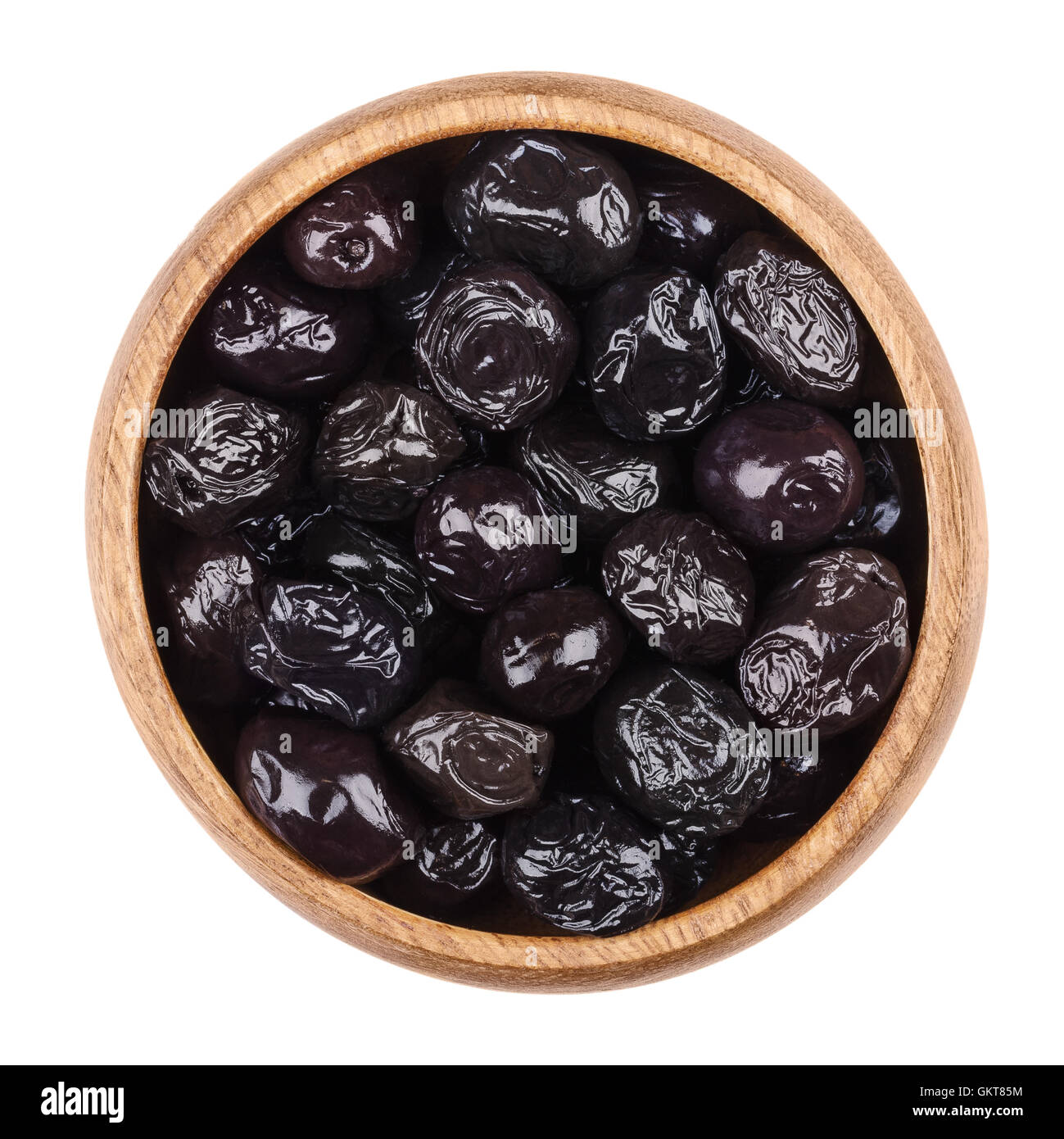 Black olives in a wooden bowl on white background. Dried ripe fruits of Olea europaea. Stock Photo