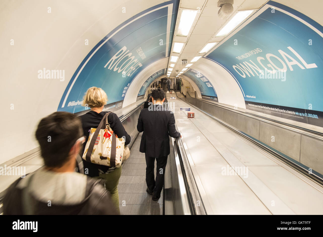 Commuters on walkway,passing,poster,ad,billboard, heading down to Tube station Bank for Bank-Waterloo line,London. London,financial,district,The City, Stock Photo