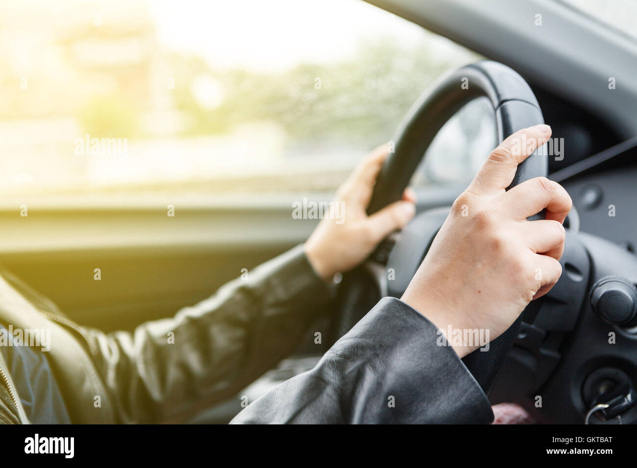 Woman driving a car, hands on steering wheel, sunrise style Stock Photo