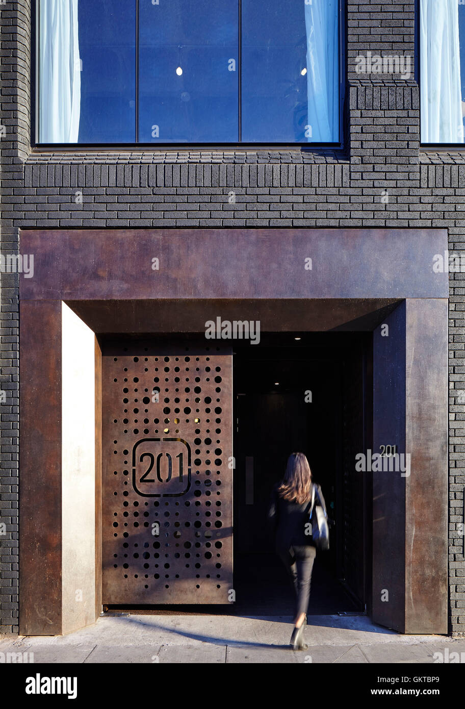 Woman entering the building through steel doorway. 201 Borough High Street, London, United Kingdom. Architect: Stiff + Trevillion Architects, 2016. Stock Photo