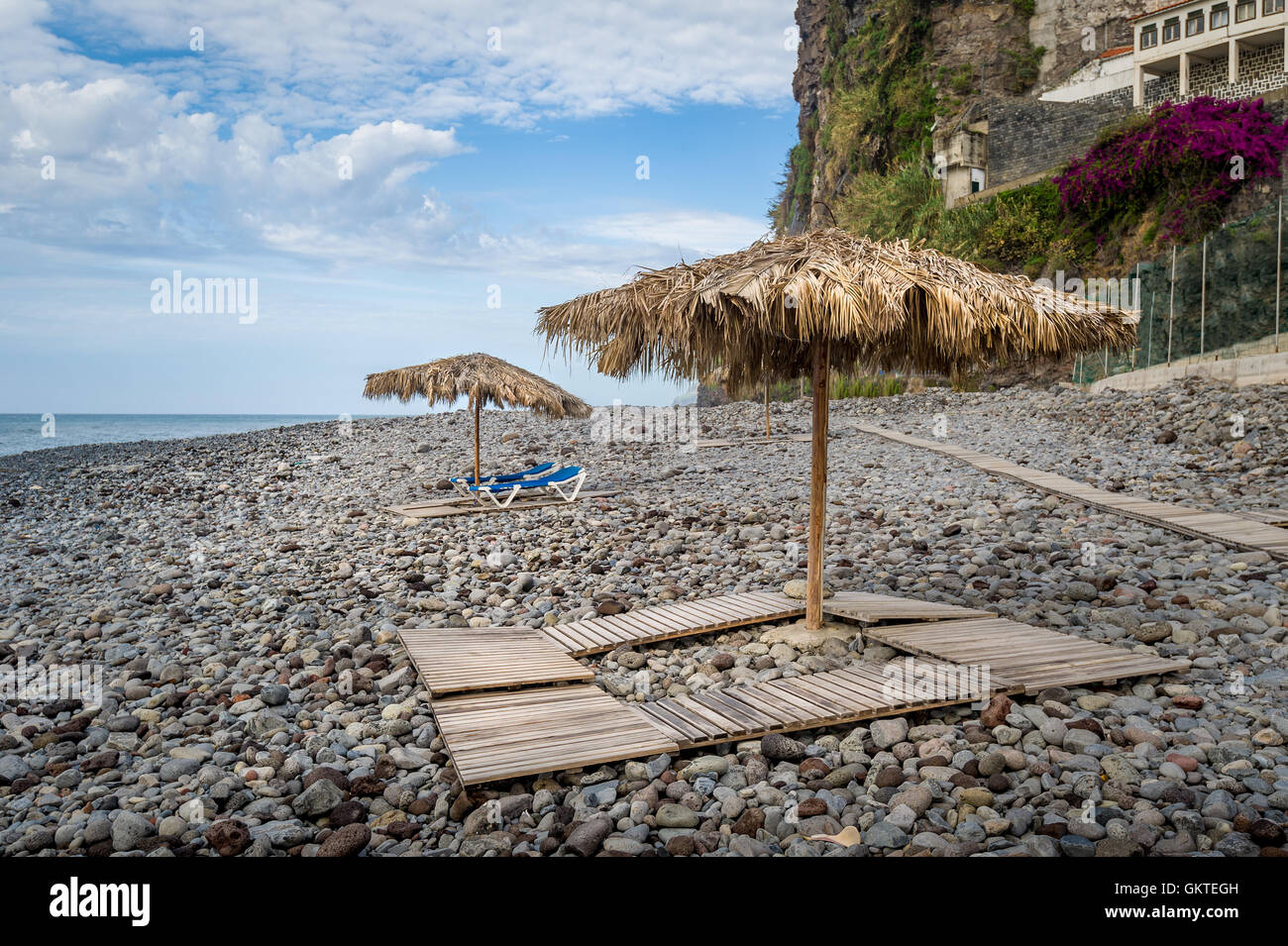 Thatched beach umbrellas and wooden beds at Ponta do Sol, Madeira island. Stock Photo