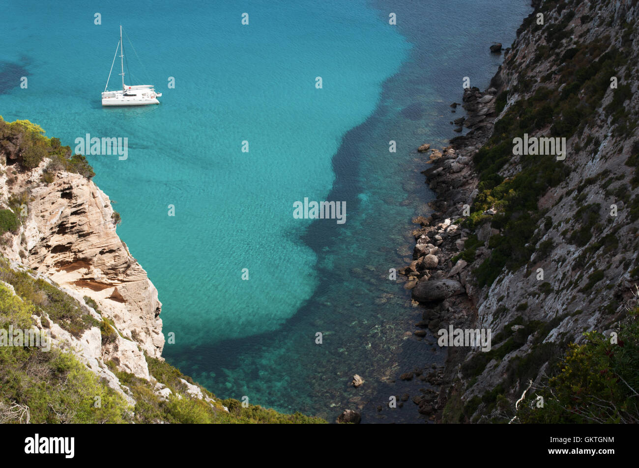 Formentera, Balearic Island: view of the Mediterranean maquis and a catamaran in the Mediterranean Sea Stock Photo