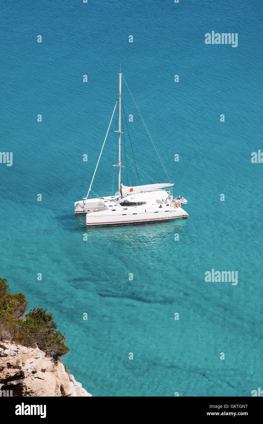 Formentera, Balearic Island: view of the Mediterranean maquis and a catamaran in the Mediterranean Sea Stock Photo