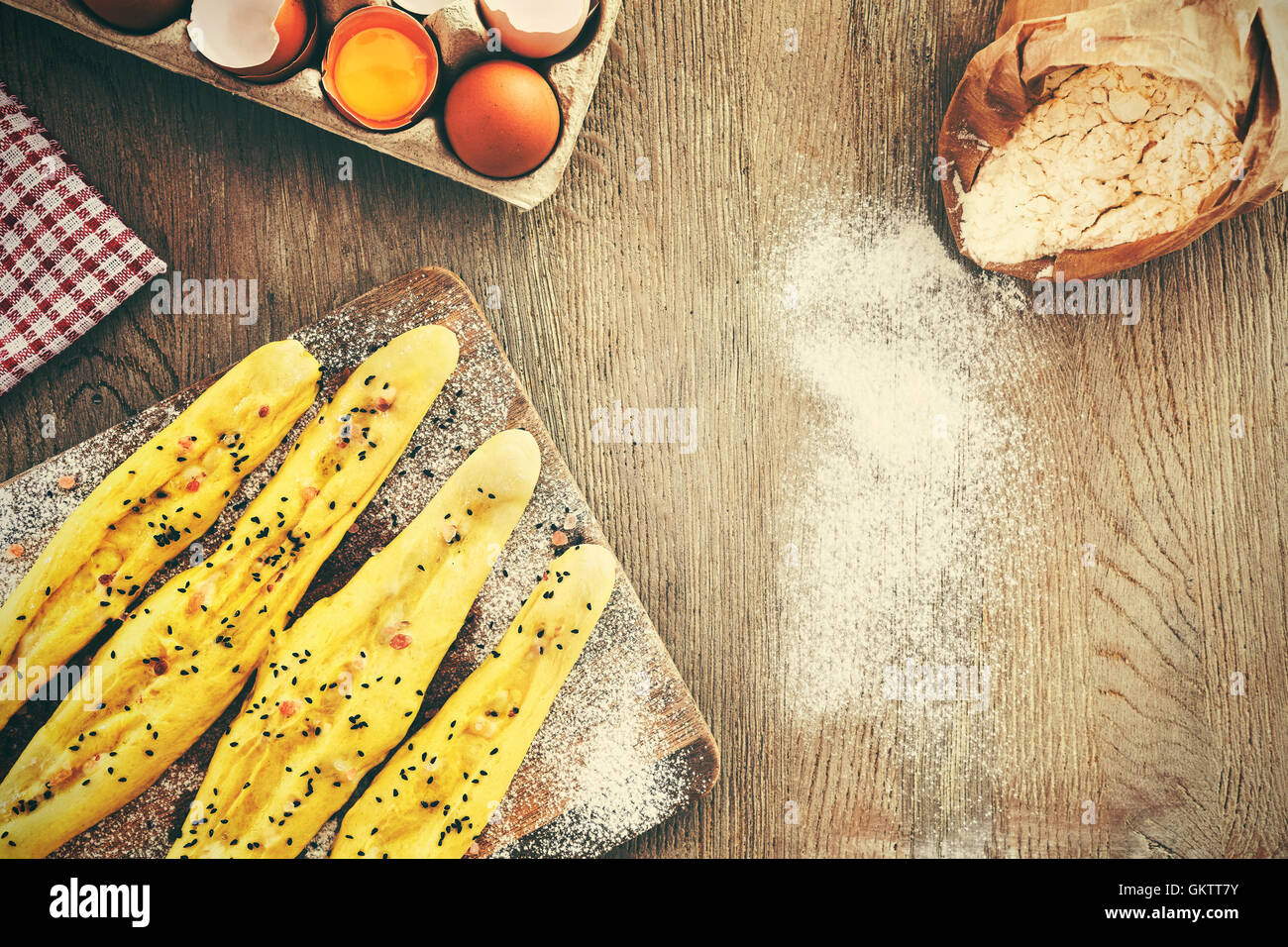 Vintage filtered raw bread sticks ready for baking, rustic setting on a wooden table, space for text. Stock Photo