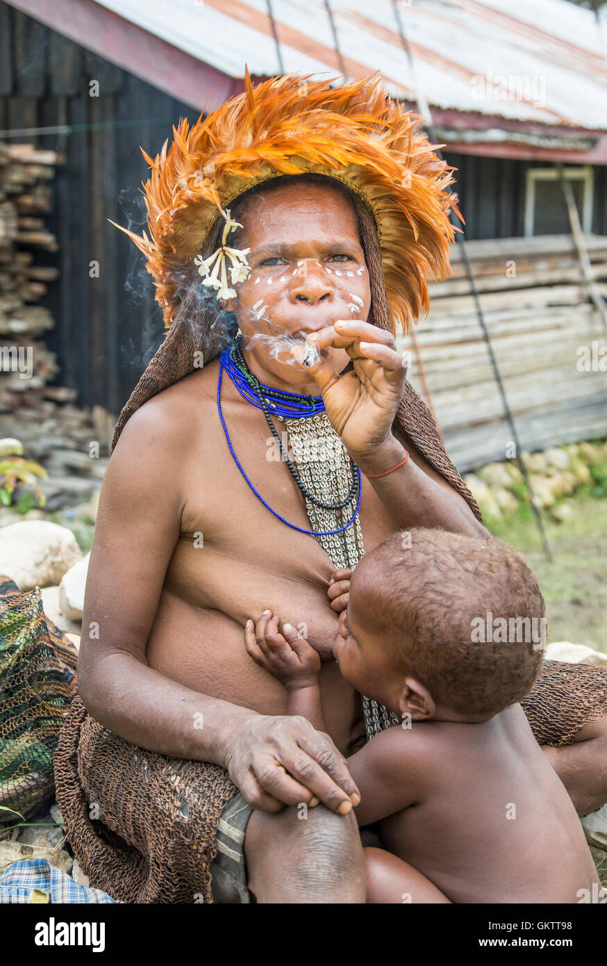 Baliem Valley, West Papua, Indonesia, February 15th, 2016: Dani tribe woman smoking and breastfeeding her baby Stock Photo