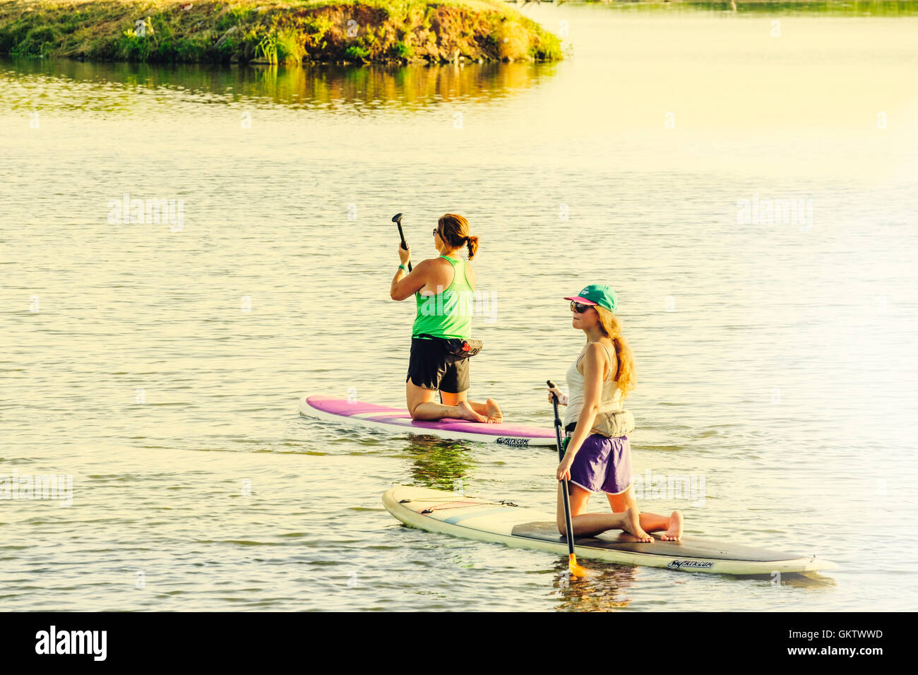 Two young Caucasian women enjoy paddleboarding on the North Canadian river near Bethany and Oklahoma City in Oklahoma, USA. Stock Photo