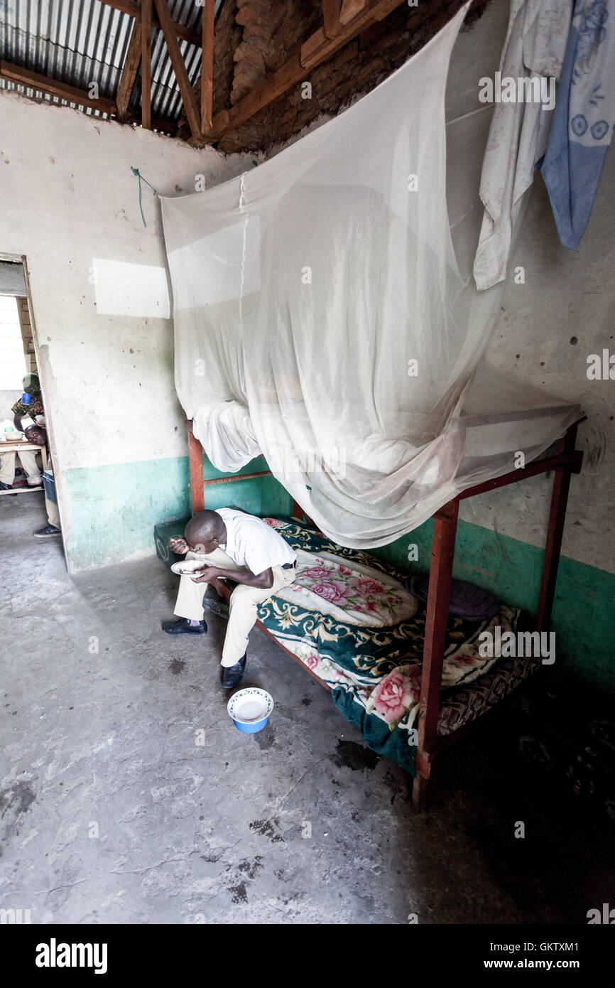 A young man eats food inside is sleeping quarters inside a school Stock Photo