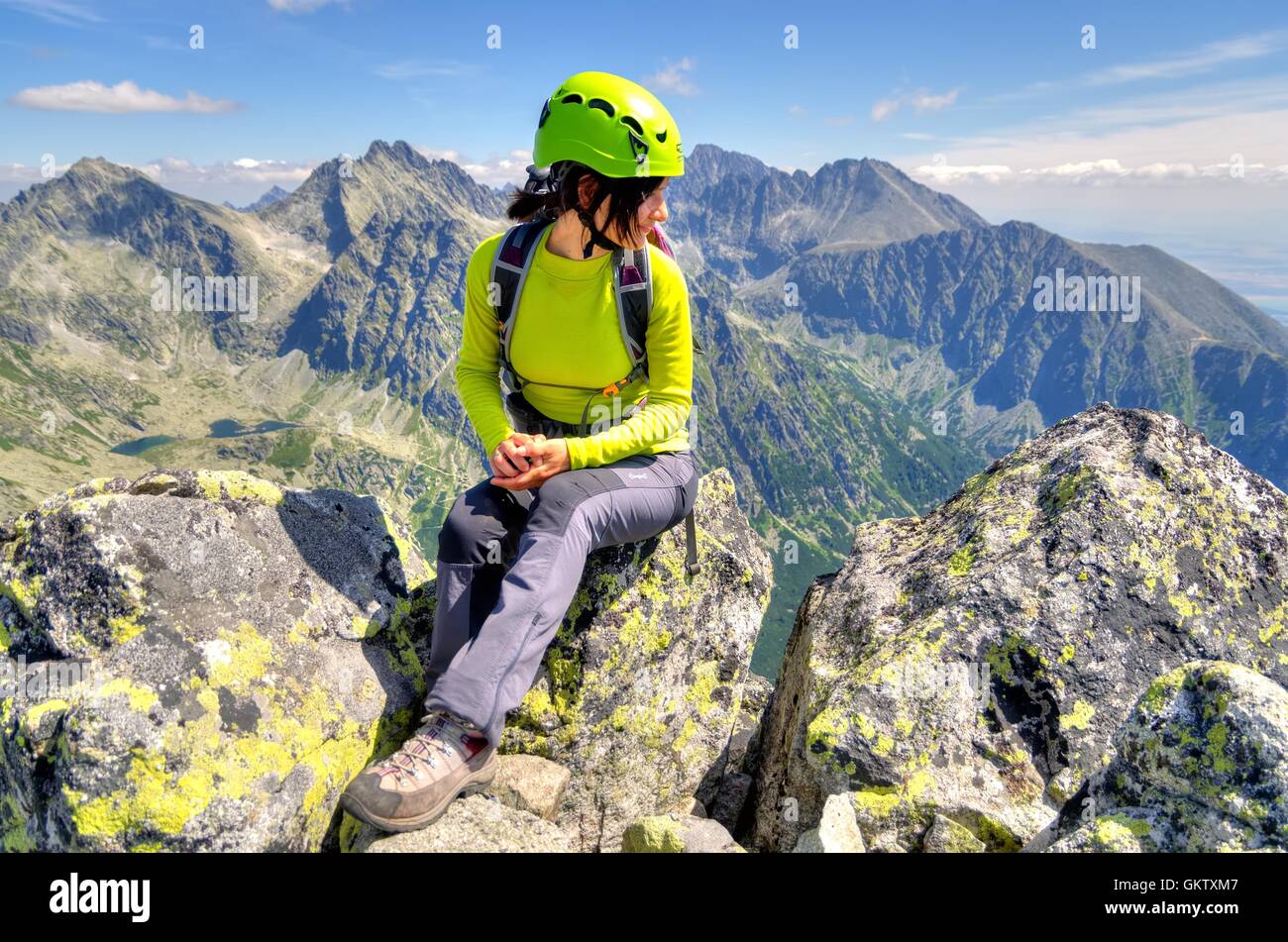 HIGH TATRA, SLOVAKIA - AUGUST 20, 2015: Tourist in the mountains. Young woman on the top admiring mountain views. Stock Photo