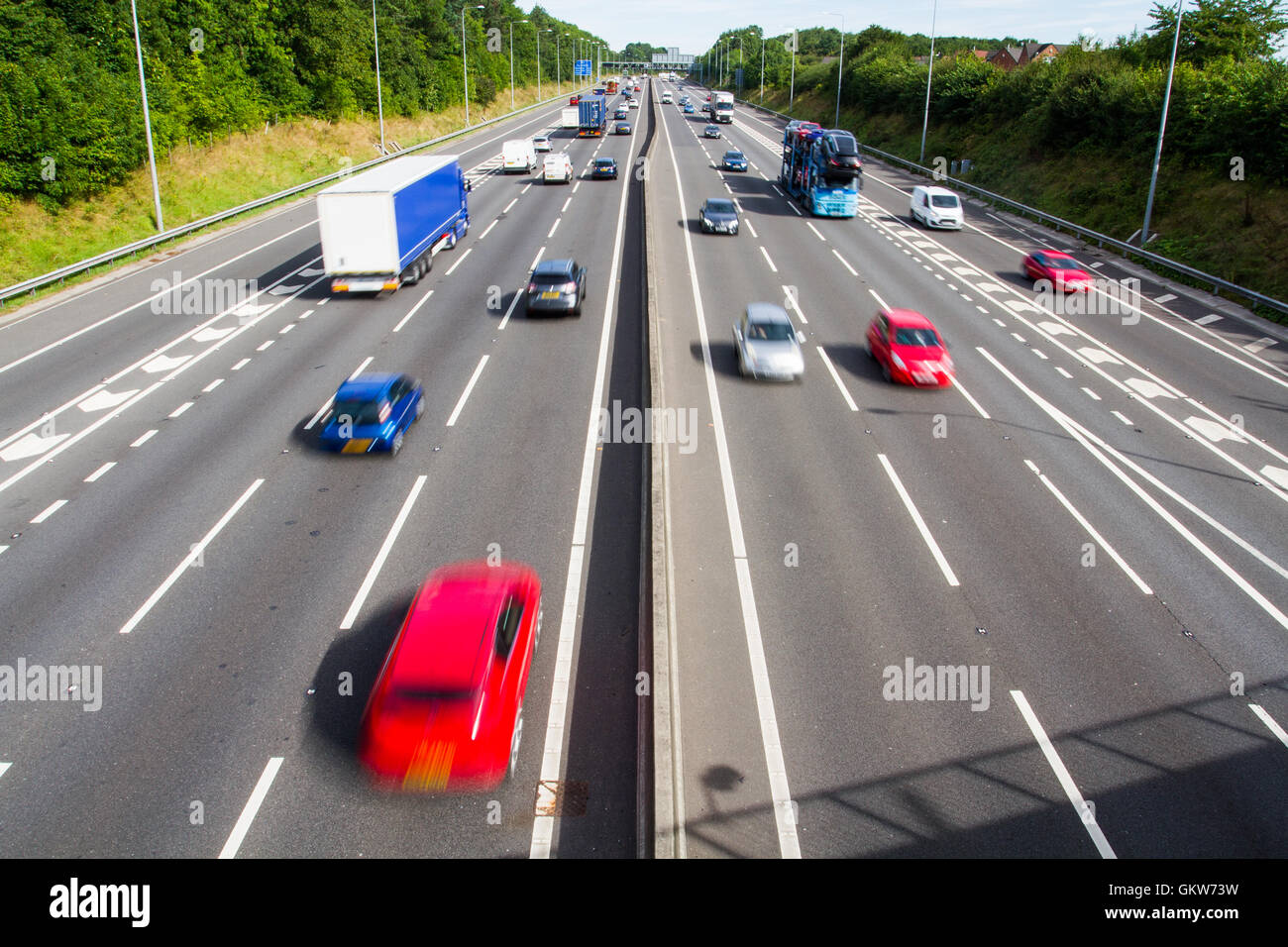 Looking down from a bridge onto the two carriageways of a busy motorway or highway full of fast moving traffic. Stock Photo