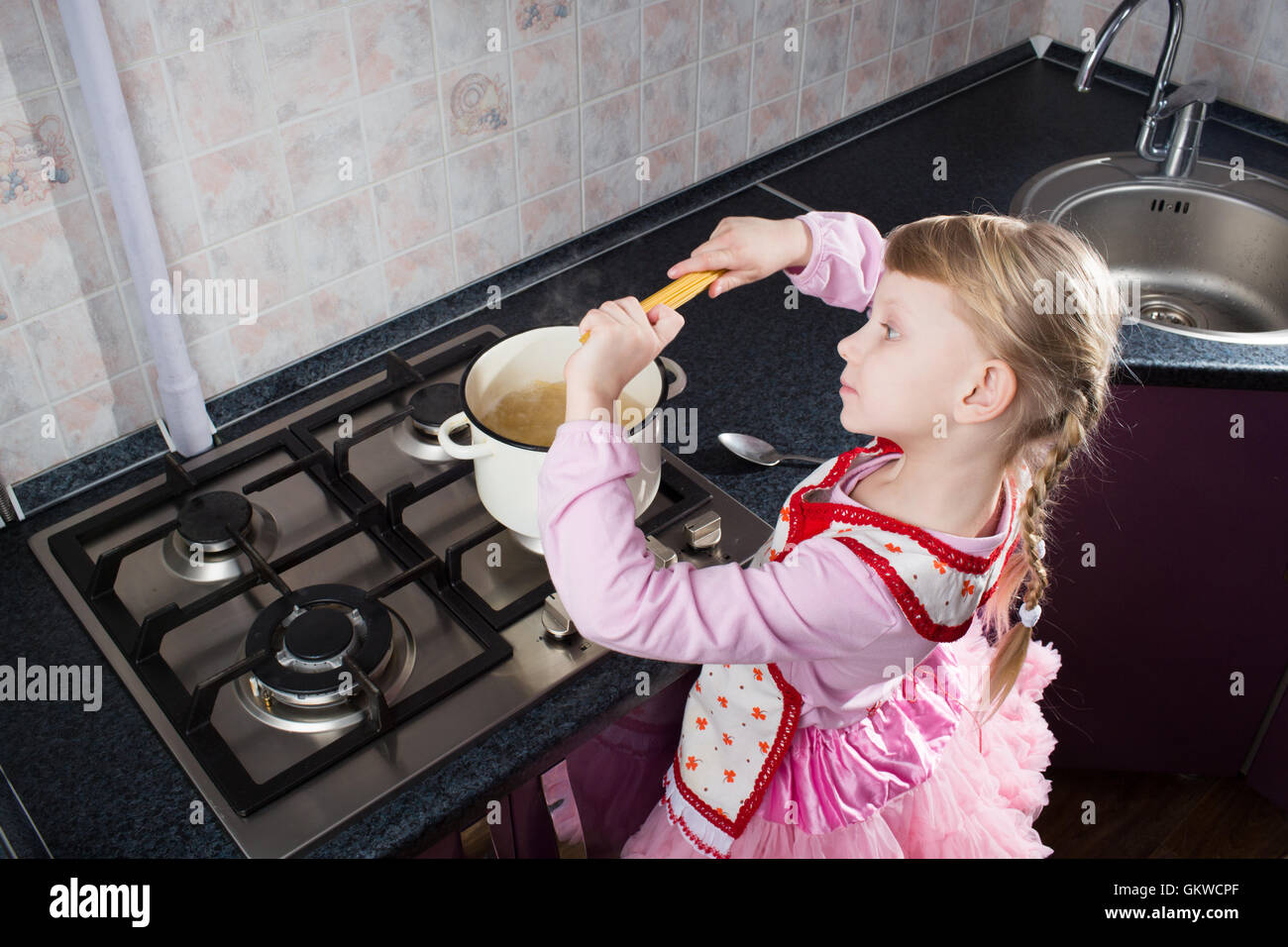 little girl putting pasta in the pot Stock Photo Alamy