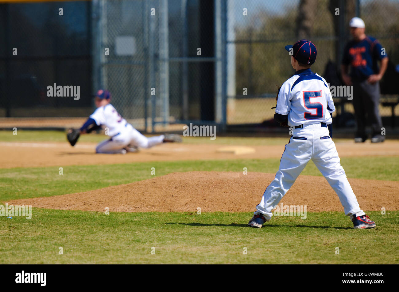 Youth pitcher after throw to first Stock Photo Alamy