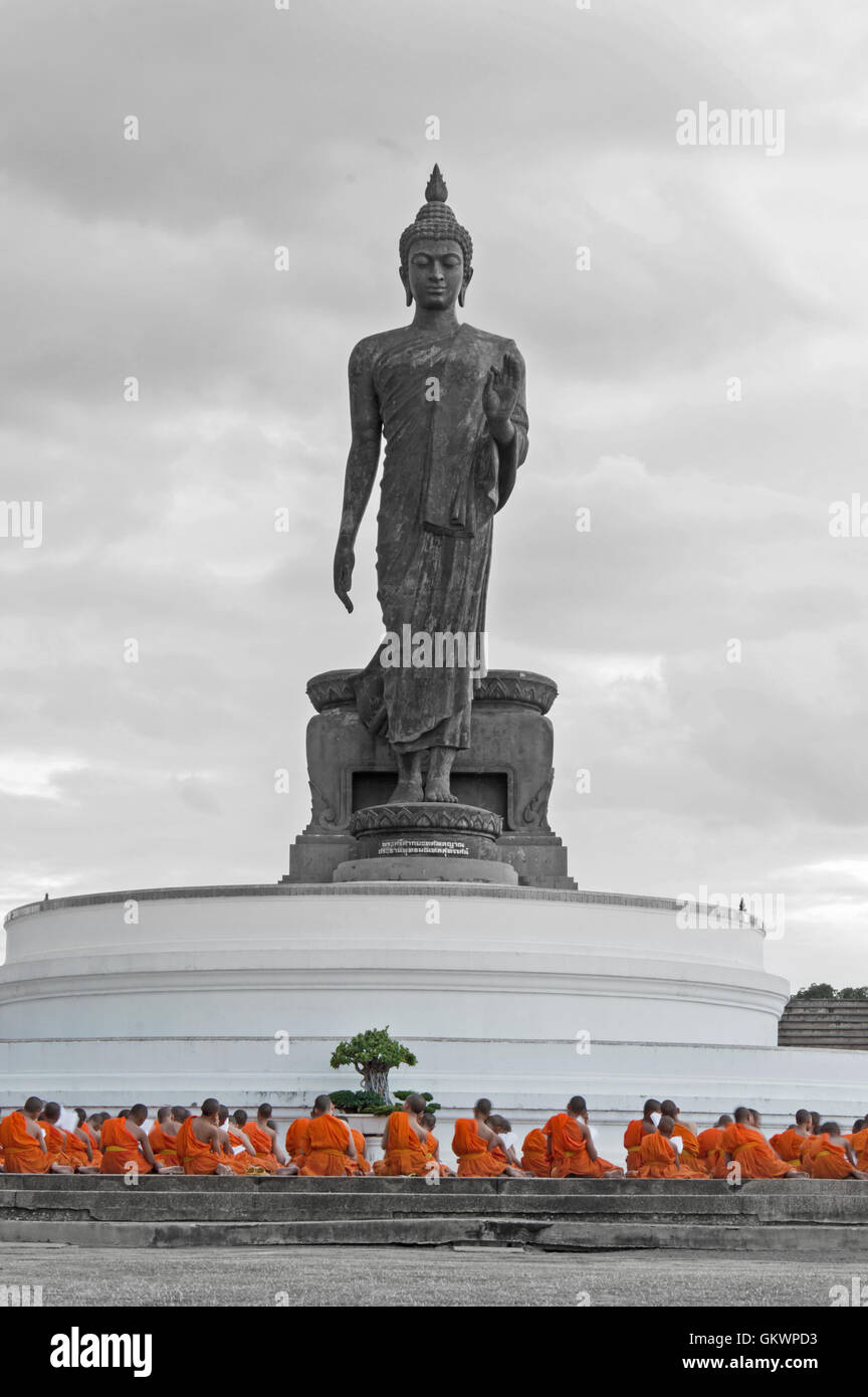 Nakhon Pathom, Thailand - August 4, 2016: Buddhist monks praying in front of walking Buddha statue at Buddhamonthon (Phutthamont Stock Photo