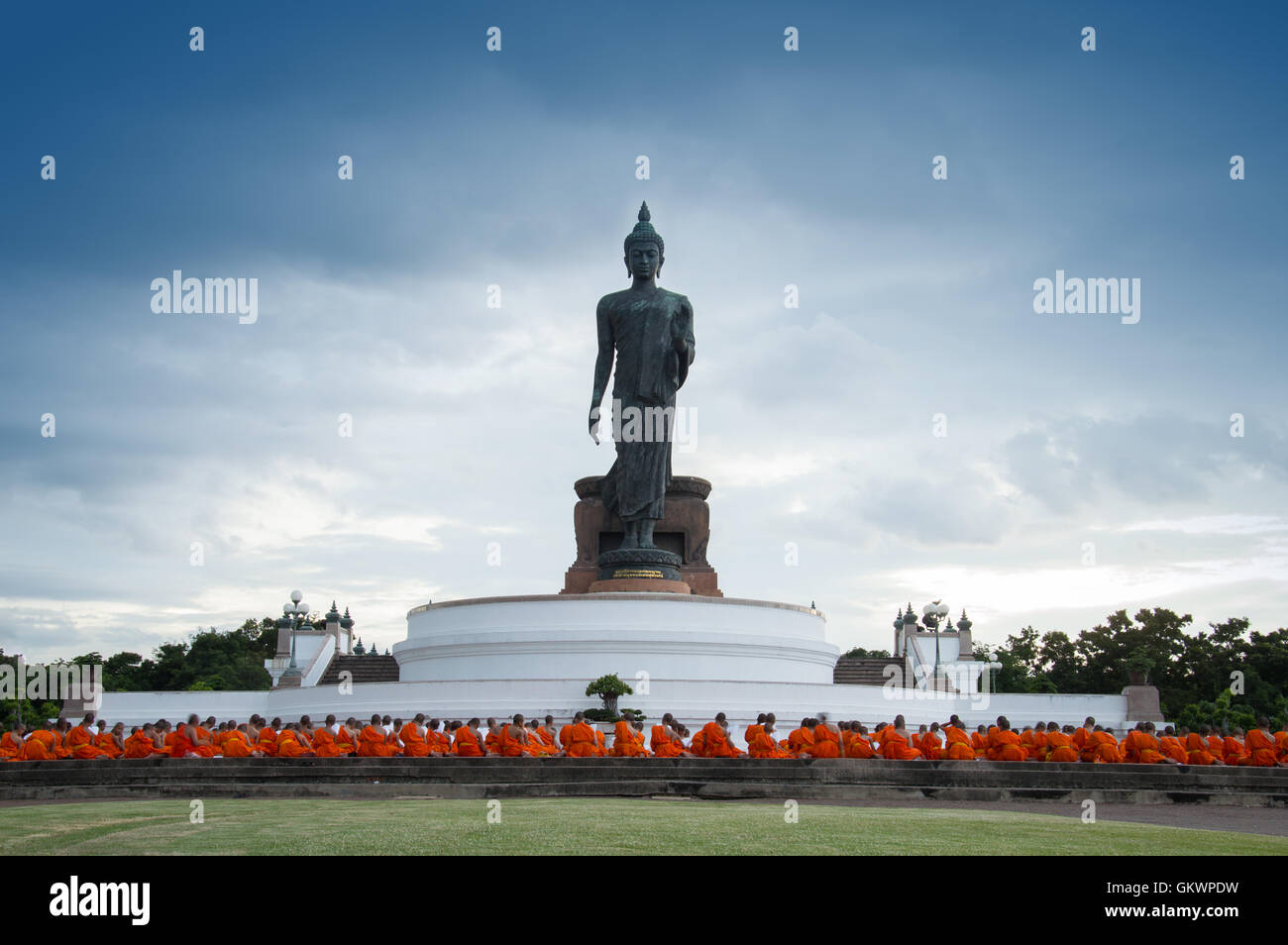 Nakhon Pathom, Thailand - August 4, 2016: Buddhist monks praying in front of walking Buddha statue at Buddhamonthon Stock Photo