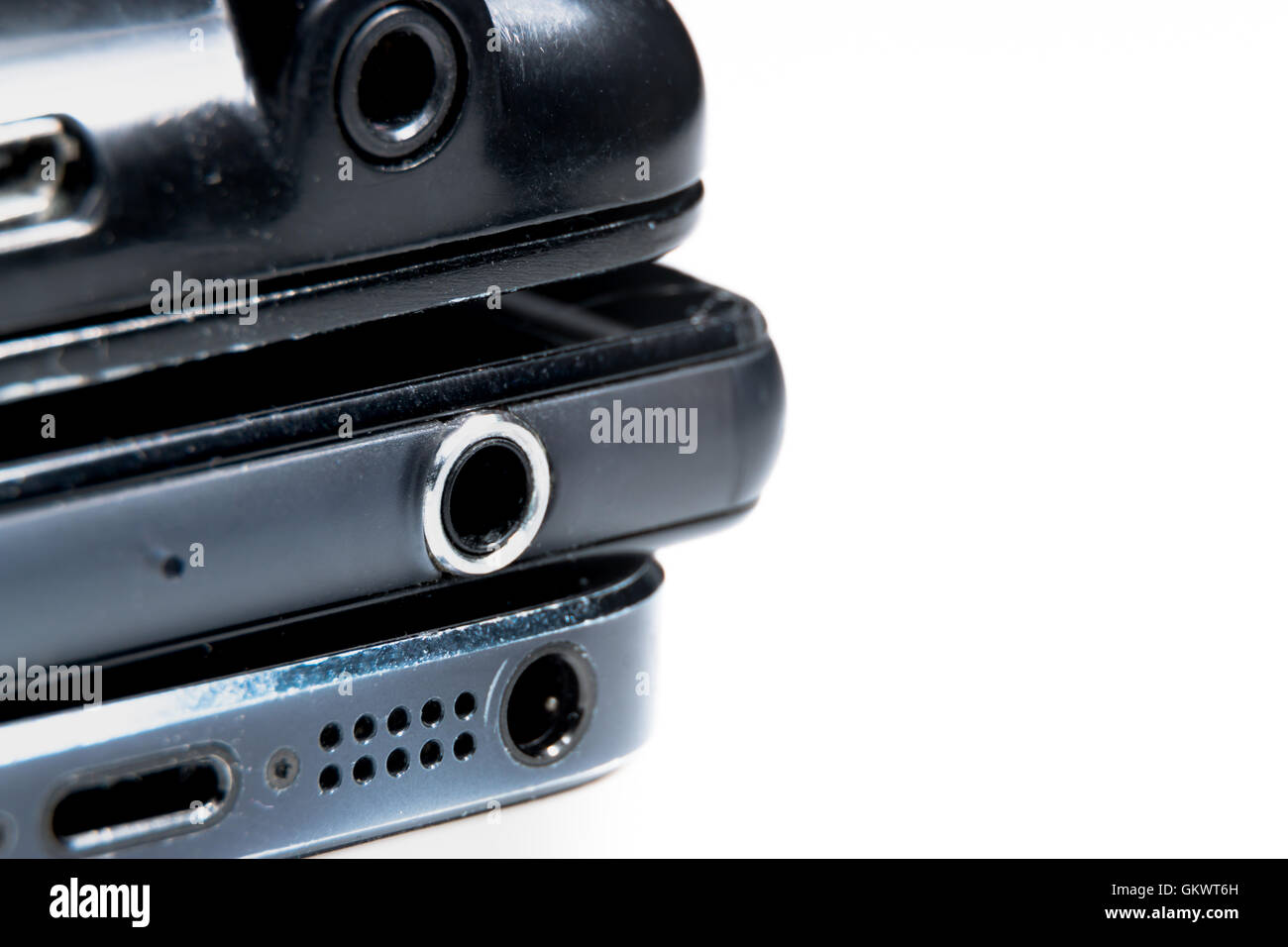 Close up of three 3.5mm headphone jacks on an android smartphone, iphone and portable radio. Stock Photo
