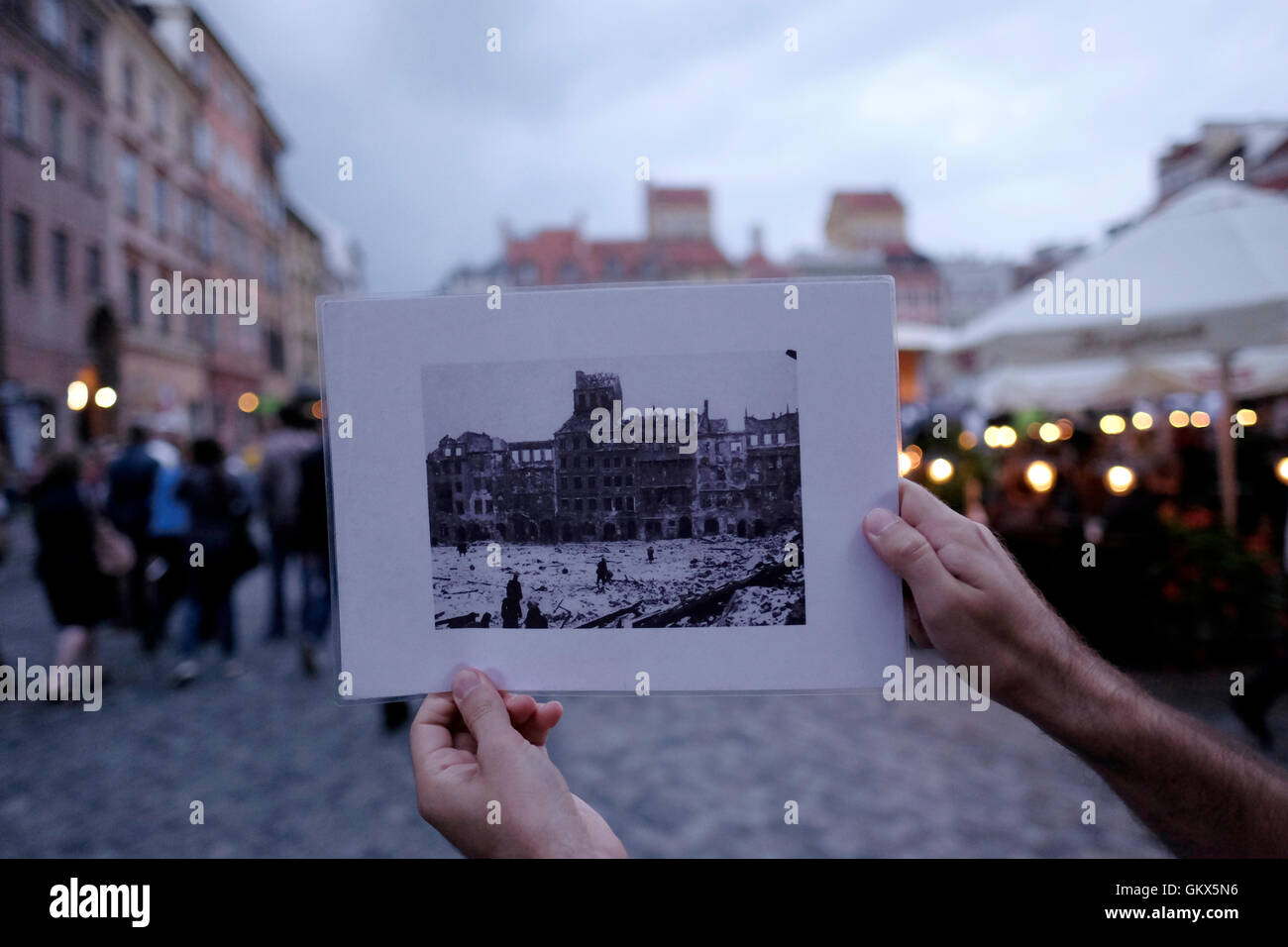 A person holds an old black and white photo of Old Town Market Place, which was systematically blown up by the German Army during World War II in the old town Stare Miasto of Warsaw, Poland Stock Photo