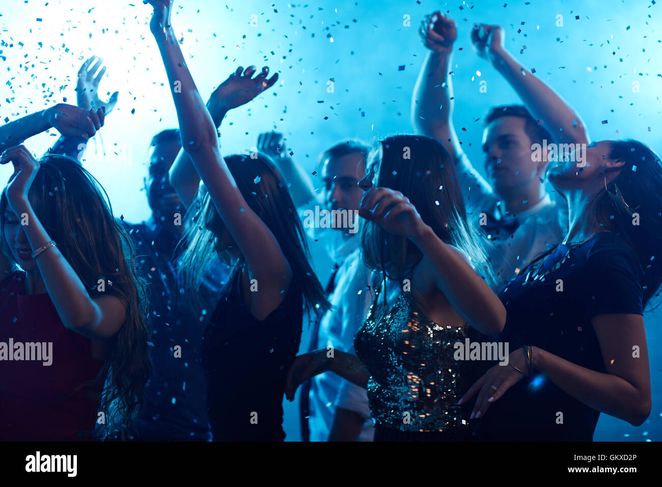 Ecstatic friends dancing in confetti in night club Stock Photo - Alamy
