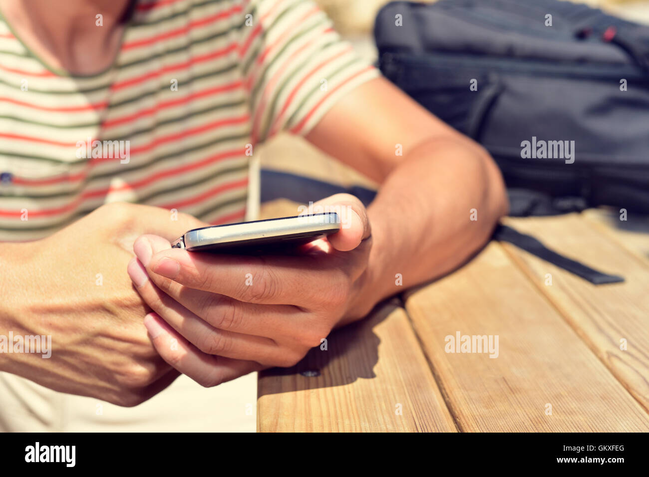 closeup of a young caucasian man sitting at an outdoor wooden table ...