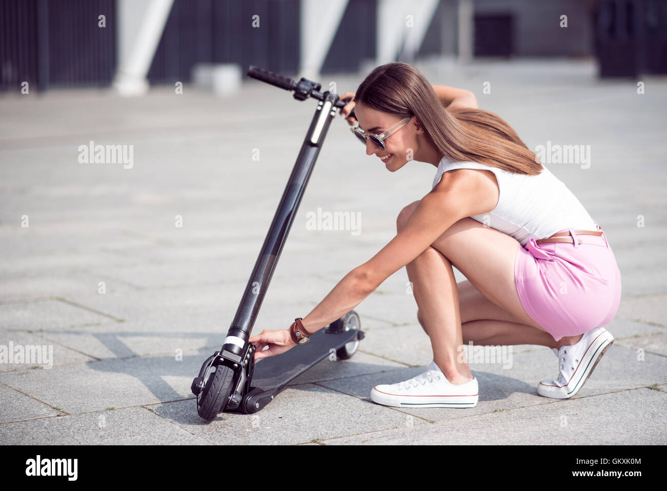 Cheerful woman using kick scooter Stock Photo