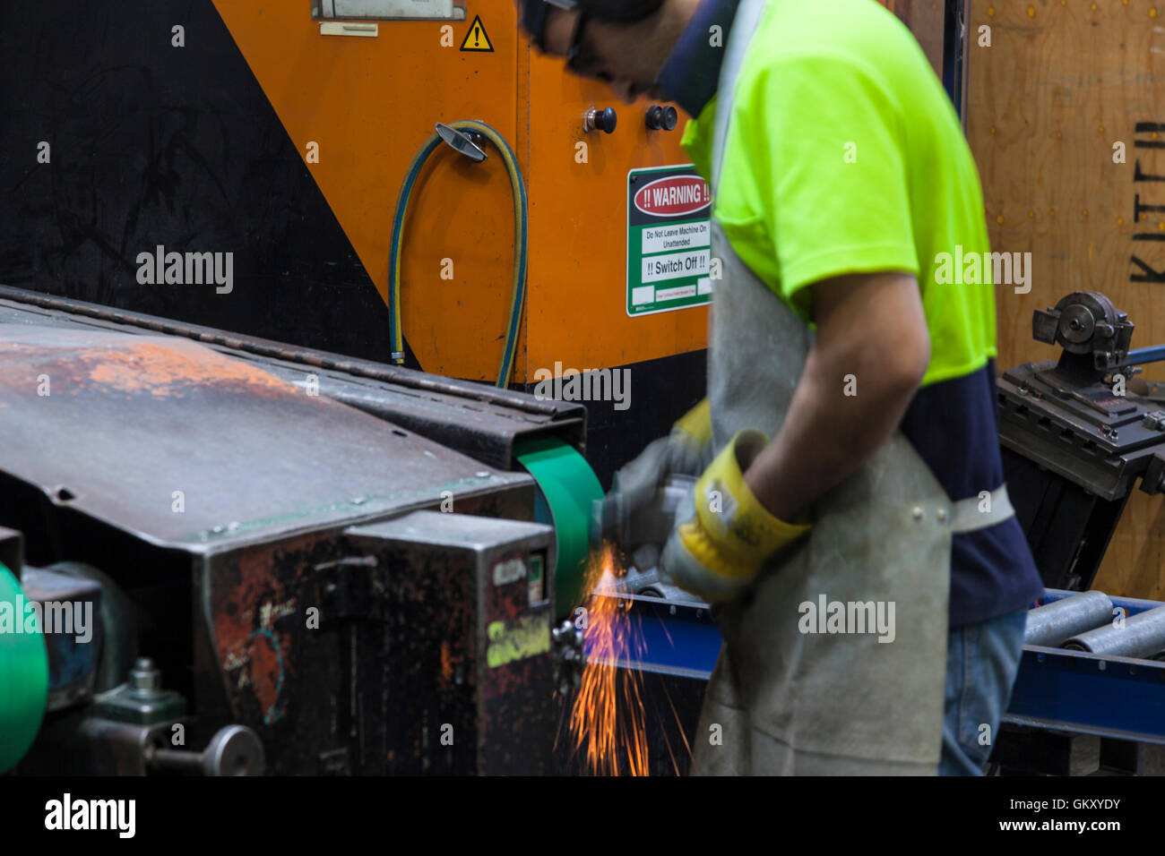 workmen in safety wear cutting, grinding metal parts for further