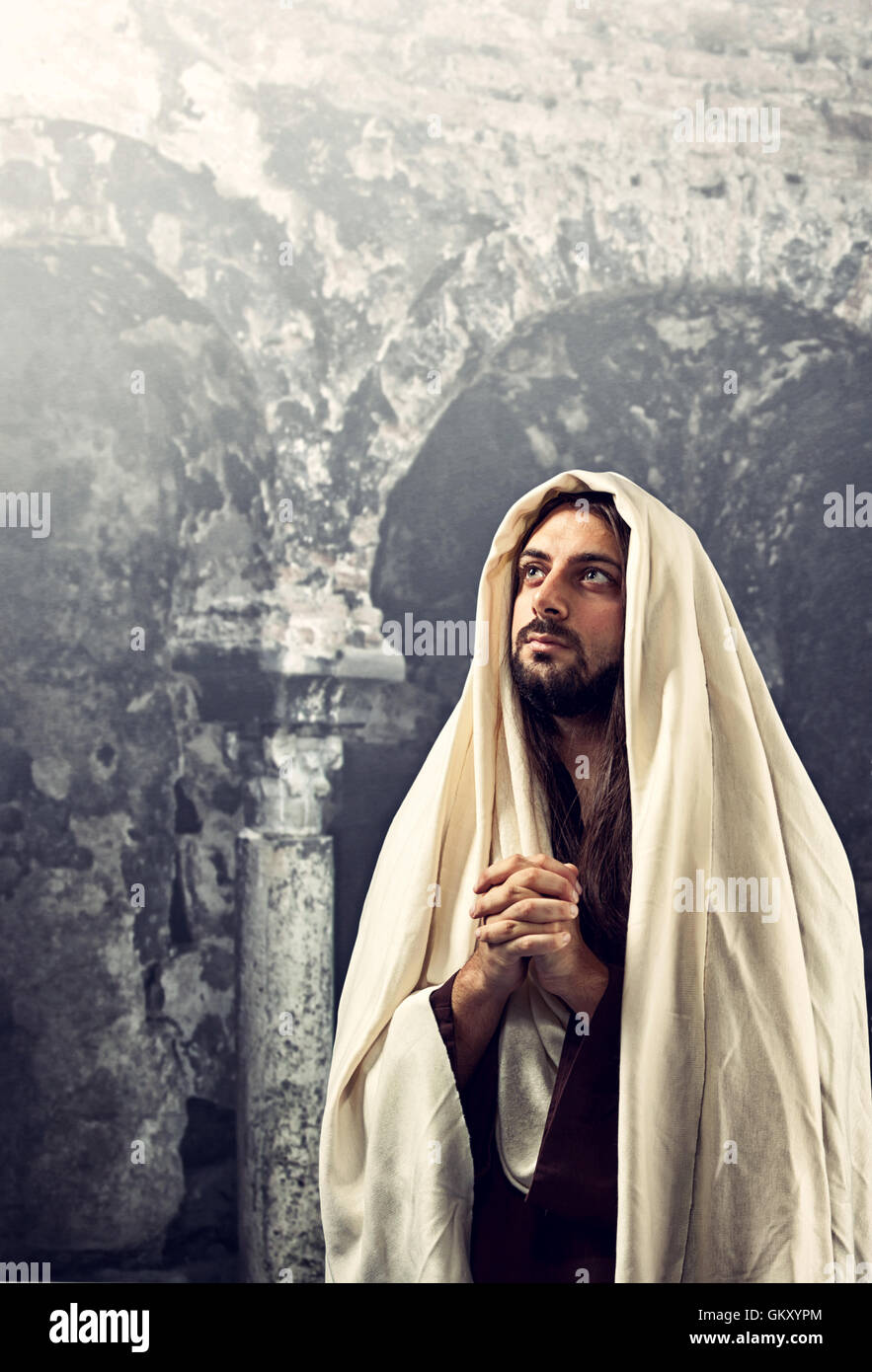Jesus Christ prays with clasped hands turning our gaze to his father. Stock Photo