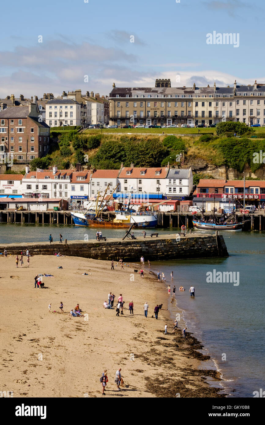 Holiday makers on the beach in Whitby harbour, North Yorkshire, England Stock Photo