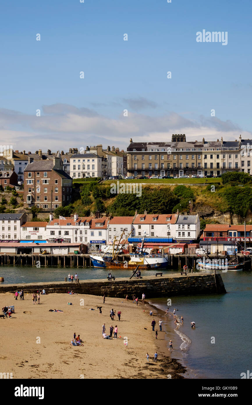 Holiday makers on the beach in Whitby harbour, North Yorkshire, England Stock Photo