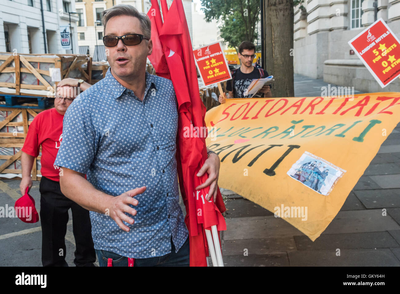 London, UK. August 23rd 2016.Unite national officer for services Rhys McCarthy speaks at the end of  protest outside the Premier Inn at London County Hall where the Hospitality Workers launch their 'Unethical London' report into the bullying, harassment and victimisation of workers in London's top hotels, where management deny the right to join unions and bargain for better wages and conditions. Two thirds of hospitality workers earn less than the London Living Wage. Peter Marshall/Alamy Live News Stock Photo