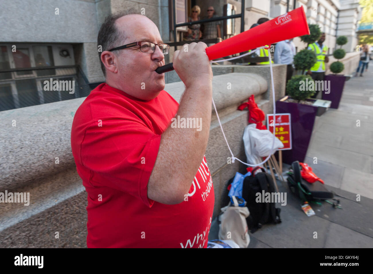 London, UK. August 23rd 2016. Unite Hospitality Workers launch their 'Unethical London' report into the bullying, harassment and victimisation of workers in London's top hotels, where management deny the right to join unions and bargain for better wages and conditions with a protest outside the Premier Inn at London County Hall. A blast on a plastic horn marks the end of their protest. Peter Marshall/Alamy Live News Stock Photo