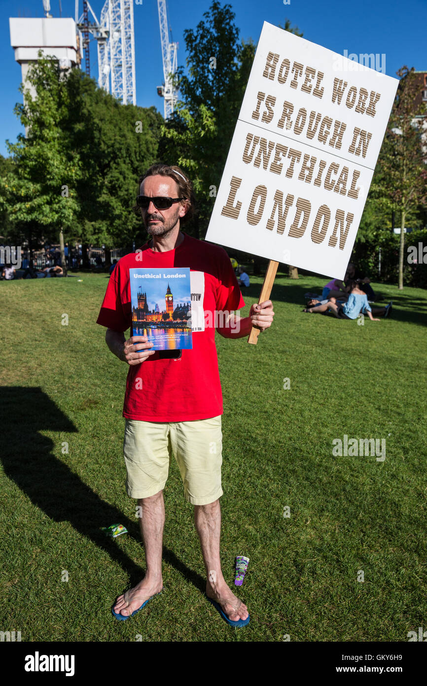 London, UK. 23rd August, 2016. A supporter of the Unite Hotel Workers Branch holds a placard and a copy of the Unethical London report, which details the manner in which workers at leading London hotels are denied access to the basic human rights of freedom of association and collective bargaining, close to the London Eye. Two-thirds of hospitality workers earn less than the London Living Wage. Credit:  Mark Kerrison/Alamy Live News Stock Photo