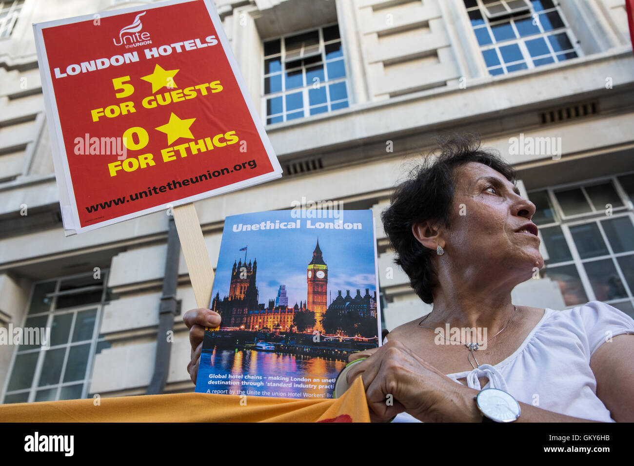 London, UK. 23rd August, 2016. A member of the Unite Hotel Workers Branch holds a placard and a copy of the Unethical London report, which details the manner in which workers at leading London hotels are denied access to the basic human rights of freedom of association and collective bargaining, at a protest outside the Premier Inn at County Hall. Two-thirds of hospitality workers earn less than the London Living Wage. Credit:  Mark Kerrison/Alamy Live News Stock Photo