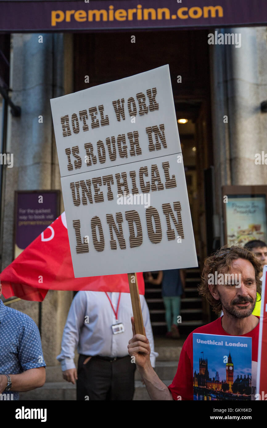 London, UK. 23rd August, 2016. A supporter of the Unite Hotel Workers Branch holds a placard and a copy of the Unethical London report, which details the manner in which workers at leading London hotels are denied access to the basic human rights of freedom of association and collective bargaining, at a protest outside the Premier Inn at County Hall. Two-thirds of hospitality workers earn less than the London Living Wage. Credit:  Mark Kerrison/Alamy Live News Stock Photo
