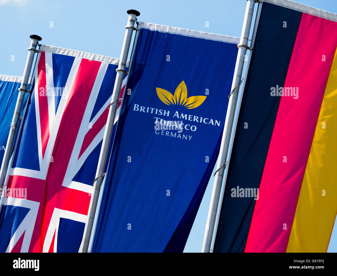 Bayreuth, Germany. 24th Aug, 2016. Between a British and a German flag is a flag with the logo of the tobacco company British American Tobacco in Bayreuth, Germany, 24 August 2016. The tobacco company plans to cut 950 positions due to heavy sales losses at Bayreuth. Photo: NICOLAS ARMER/dpa/Alamy Live News Stock Photo