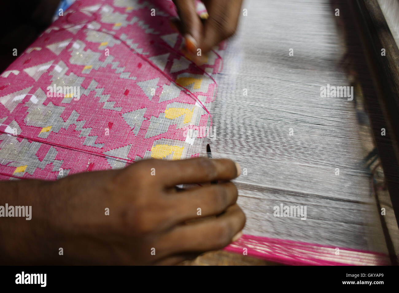 Near Dhaka, Bangladesh. 24th Aug, 2016. Handloom weaver weaves Jamdani saree on a traditional wooden hand weaving loom at Tarabo, near Dhaka, Bangladesh, August 24, 2016. Jamdani is one of the finest muslin textiles of Bengal, produced in Dhaka District, Bangladesh for centuries. The historic production of jamdani was patronized by imperial warrants of the Mughal emperors. Under British colonialism, the Bengali Jamdani and muslin industries rapidly declined due to colonial import policies favoring industrially manufactured textiles. In more recent years, the production of Jamdani has witne Stock Photo