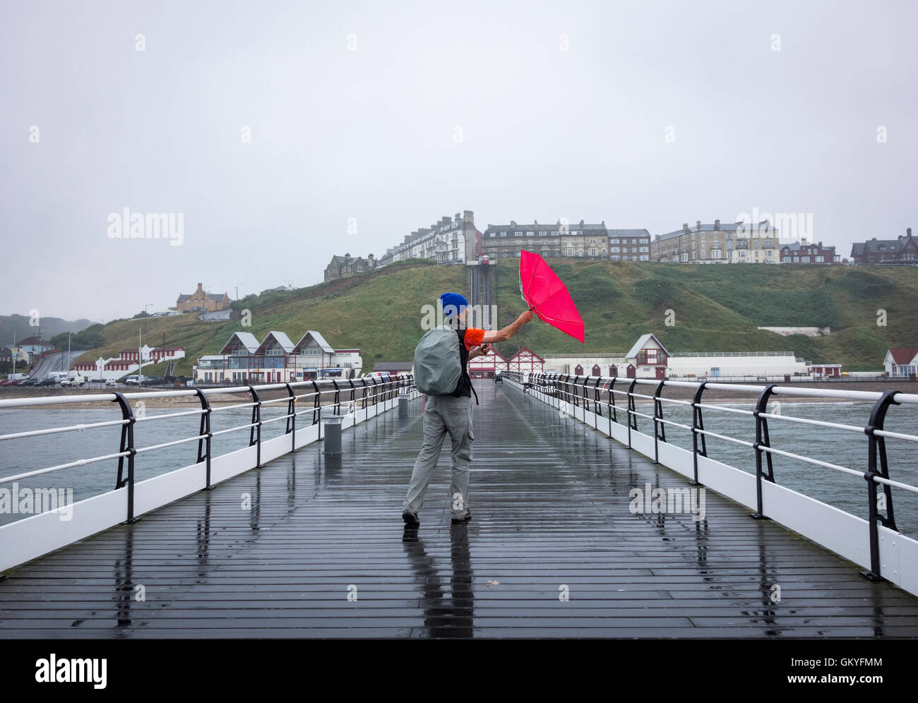 Saltburn by the sea, North Yorkshire, England, UK. 25th Aug, 2016. Weather: A hiker walking the Cleveland Way National trail on Saltburn`s Victorian pier on a wet Thursday morning on the North Yorkshire coast. A bit of a north south divide on Thursday in the UK, with much of the south enjoying warn sunshine. Credit:  Alan Dawson News/Alamy Live News Stock Photo