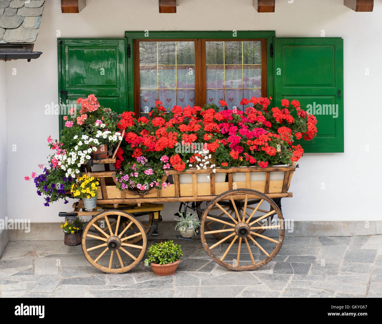 Decorative wooden cart filled with colorful summer flowers and potted plants Stock Photo