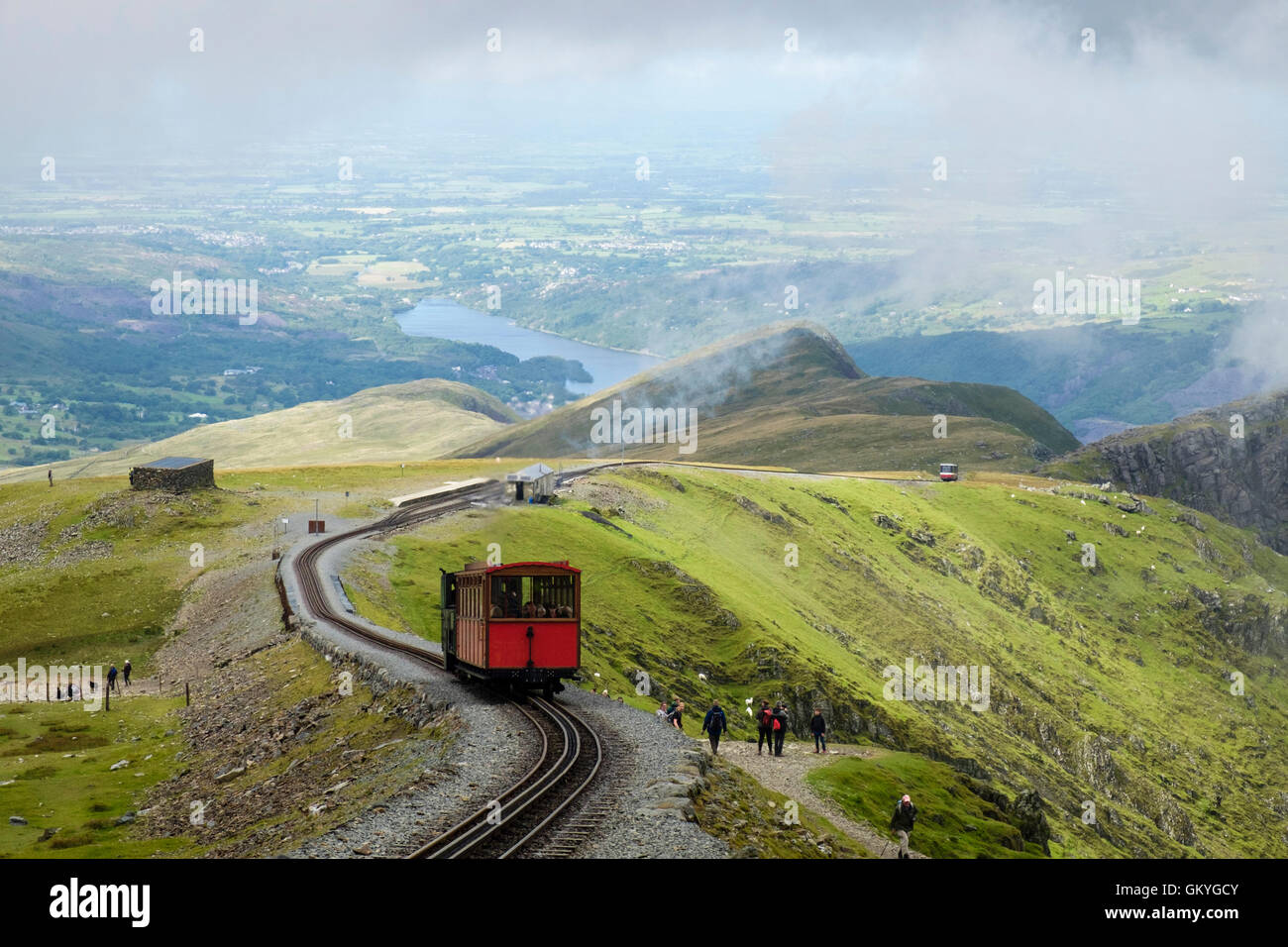 Train climbing up on Mt Snowdon Mountain Railway line above Clogwyn Station and people walking on Llanberis path in Snowdonia Wales UK Stock Photo