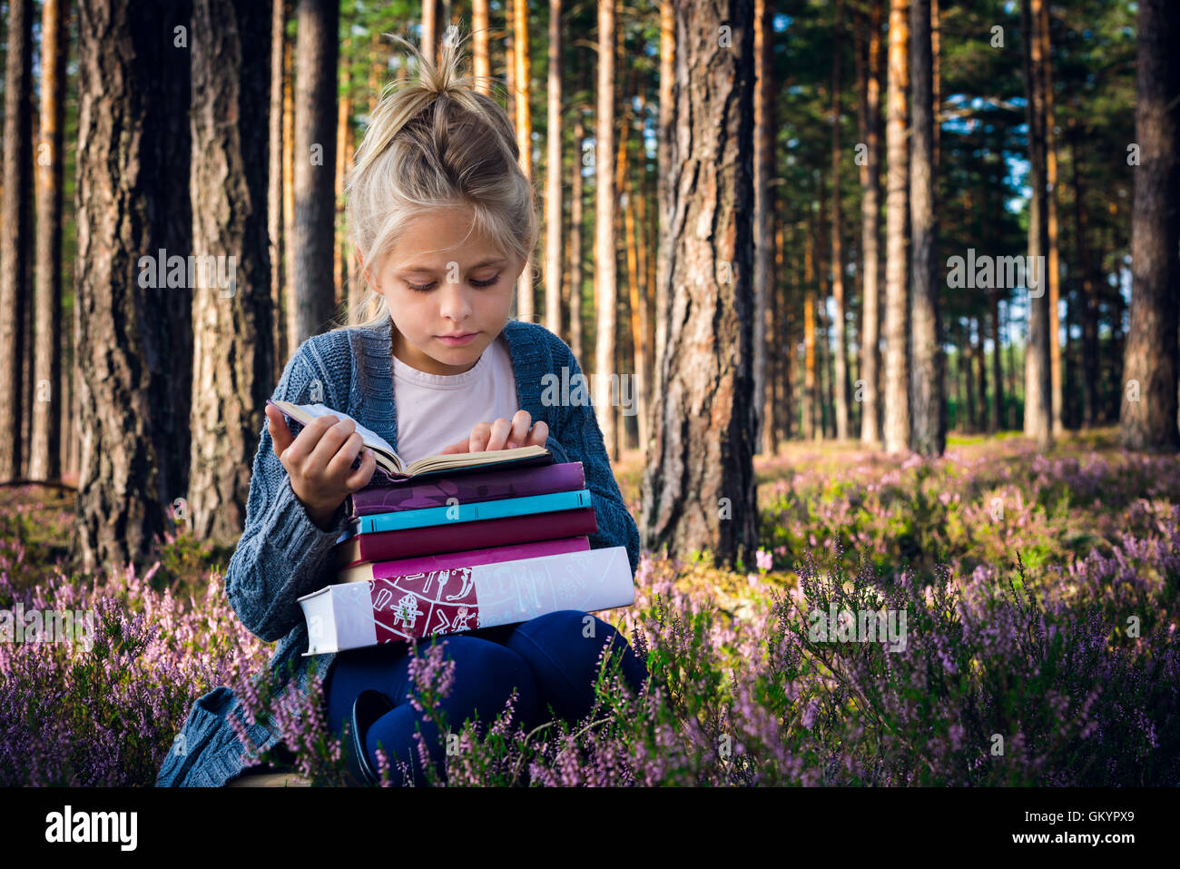 Beautiful blonde girl reading a book in the forest Stock Photo - Alamy
