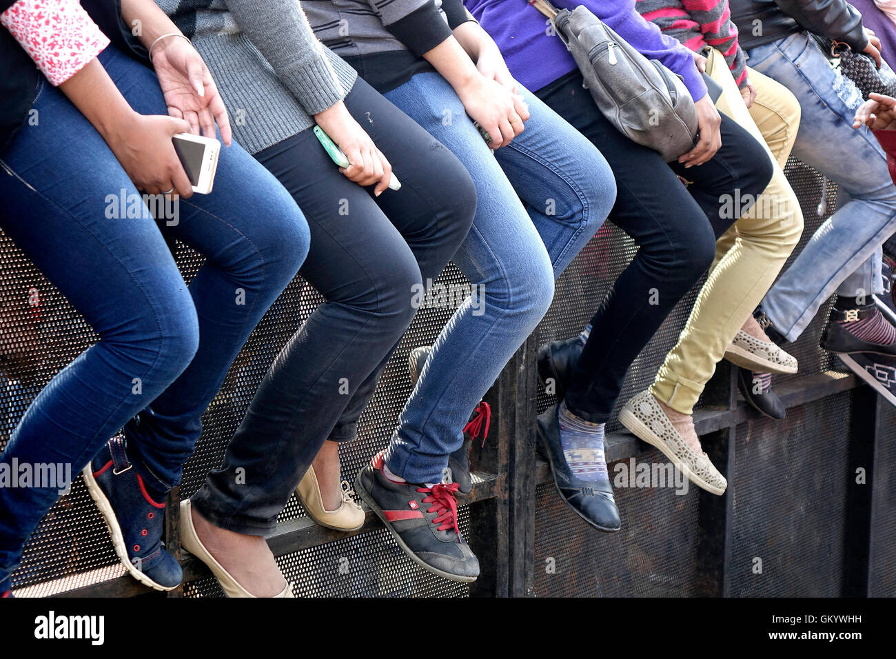 All legs.....students sitting on a ledge and watching an open air show Stock Photo