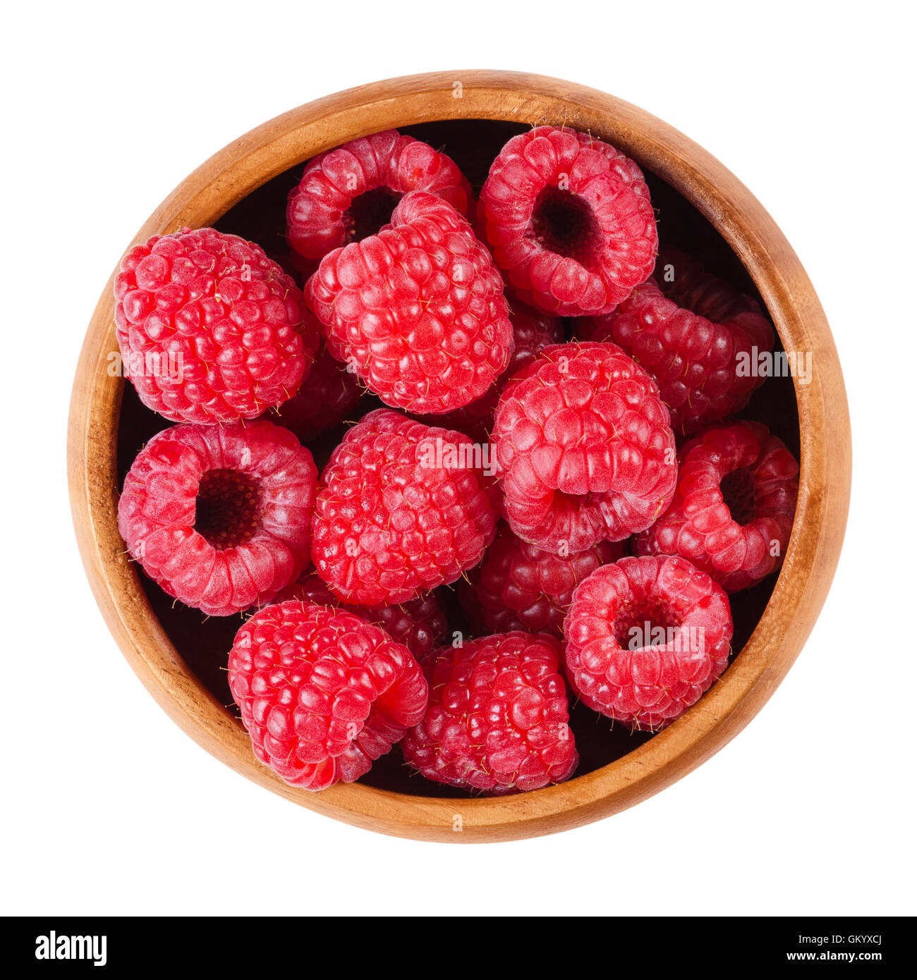 Raspberries in a wooden bowl on white background. Red ripe berries of Rubus species. Edible fruits, raw, organic and vegan food. Stock Photo