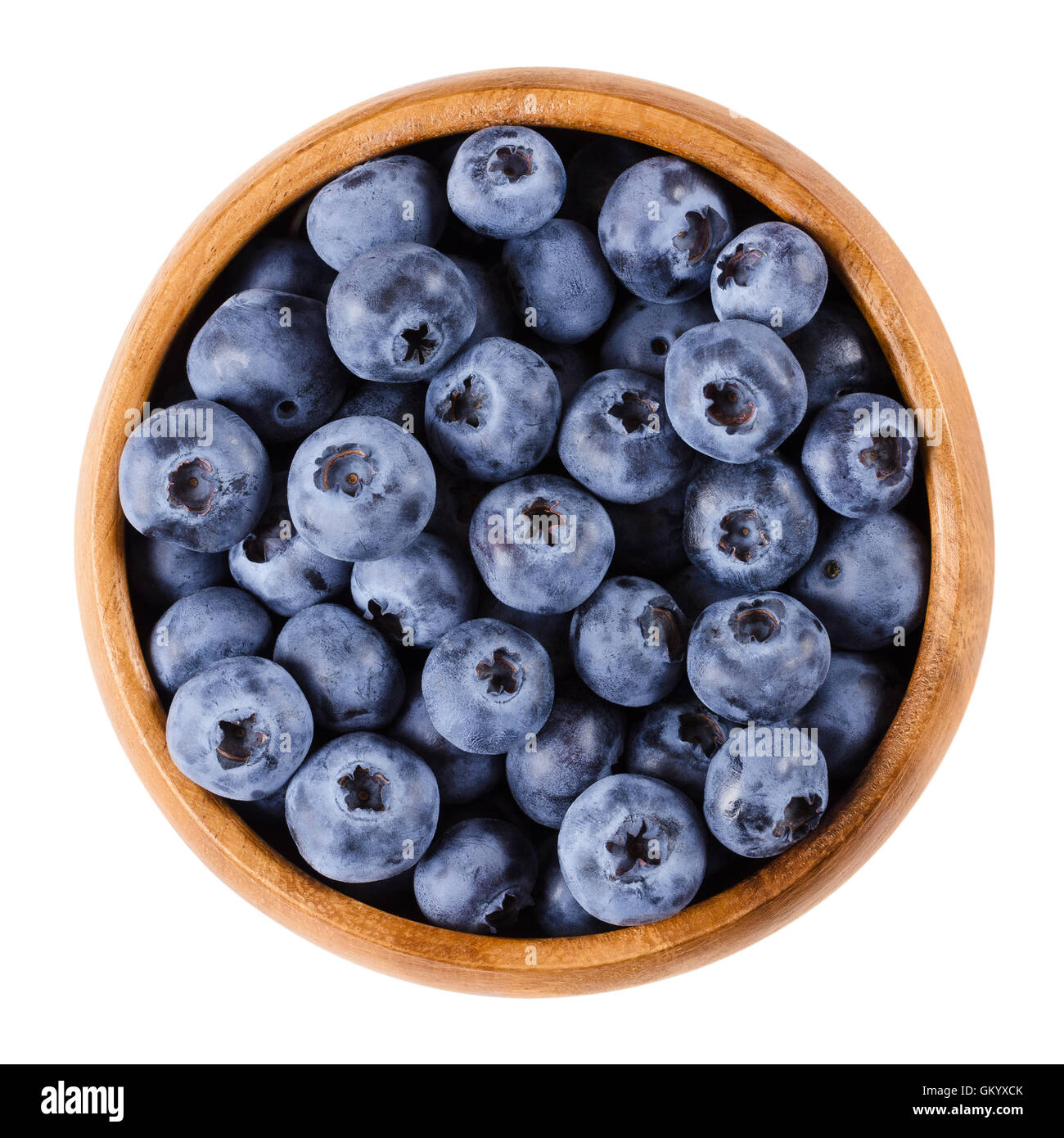 Blueberries in a wooden bowl on white background. Dark purple colored ripe berries of Vaccinium corymbosum. Edible fruits. Stock Photo