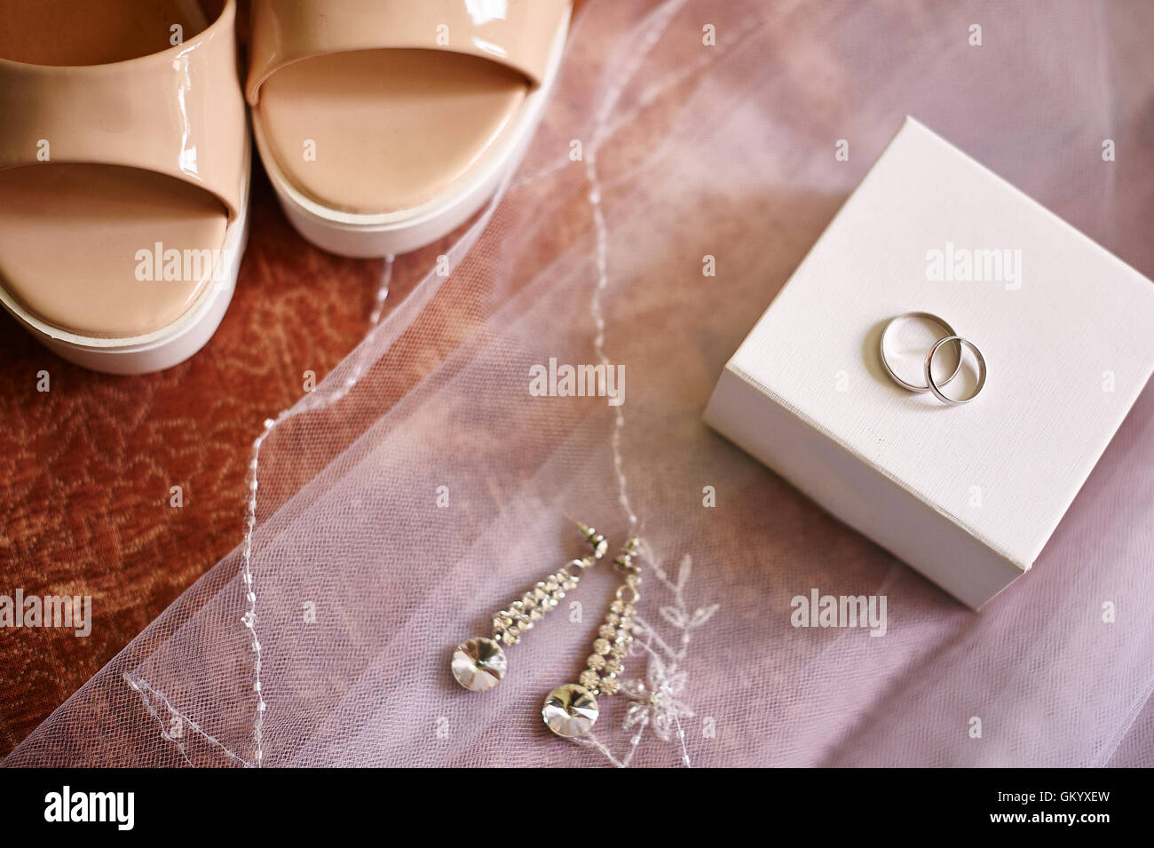 Wedding rings and earrings on a white veil of bride Stock Photo