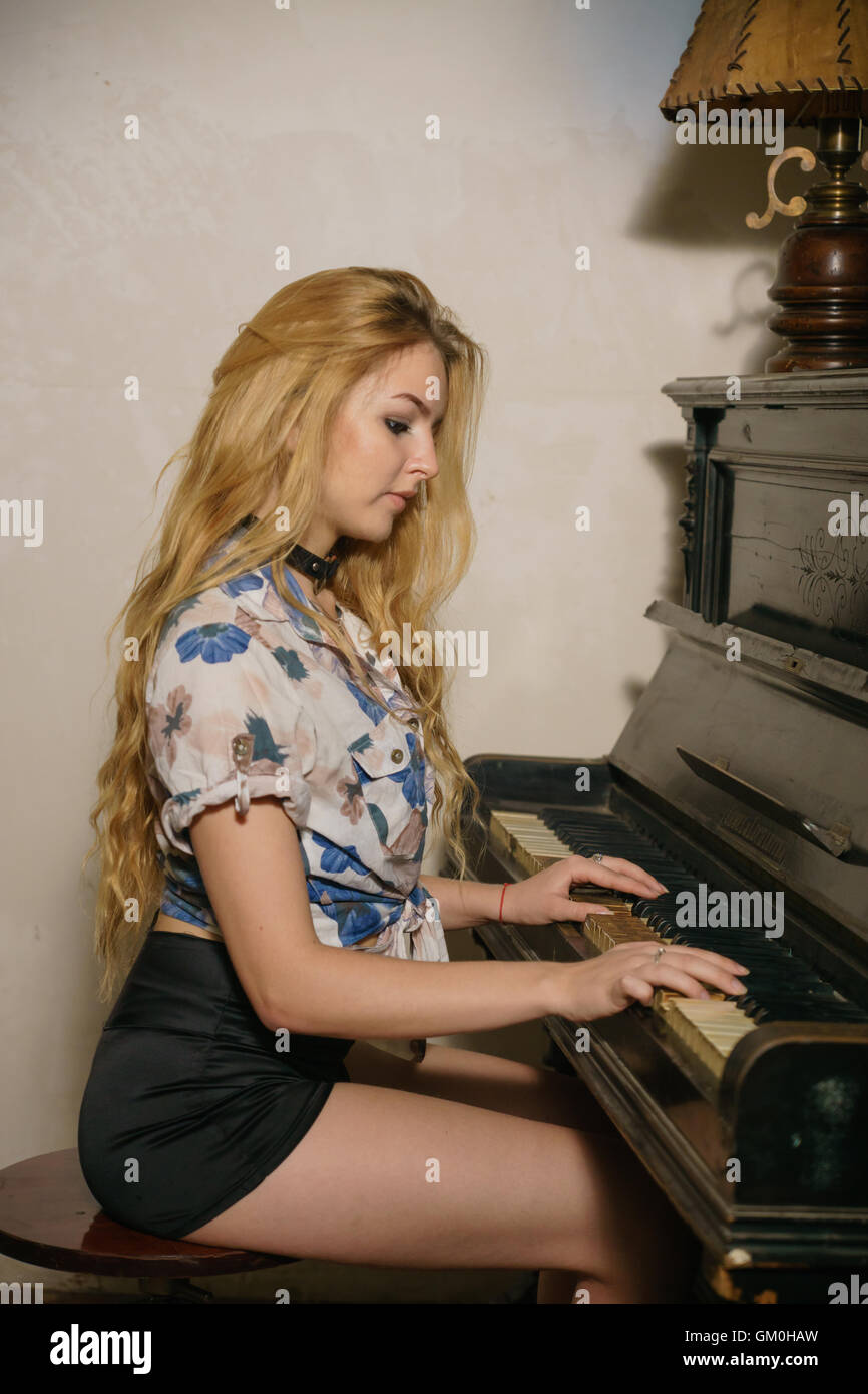 nice blonde girl with loose hair is playing on the piano Stock Photo