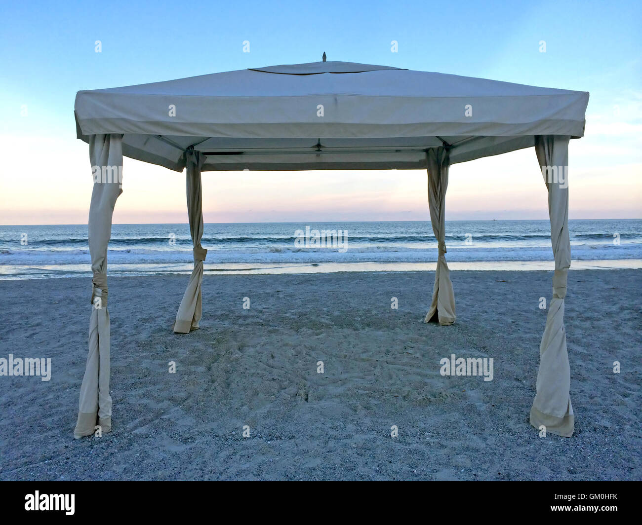 A cabana with it's sides tide back on the beach at sunset Stock Photo