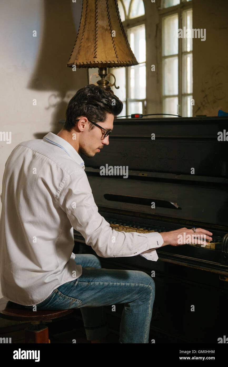 dark-haired man is playing on the piano sitting on the chair. He is inspired by this game Stock Photo