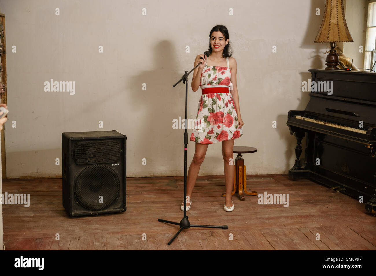 Beautiful brunette stands keeps the microphone in her hand and smiles Stock Photo