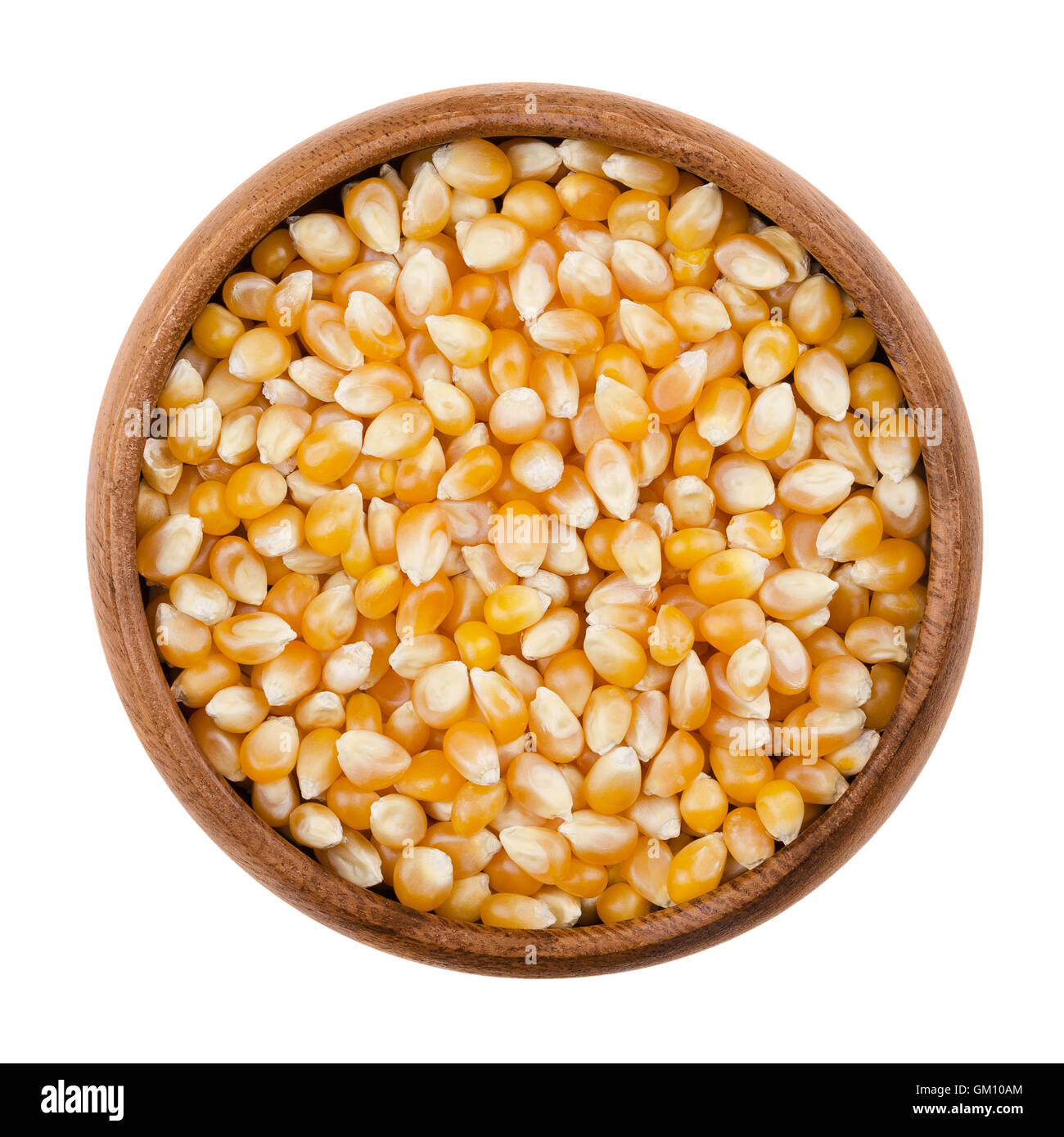 Unpopped popcorn in a wooden bowl on white background. A type of corn that expands from the kernel and puffs up when heated. Stock Photo
