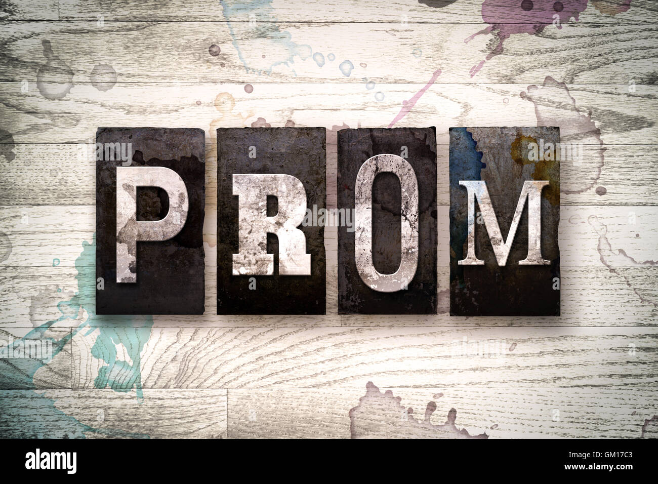 The word 'PROM' written in vintage dirty metal letterpress type on a whitewashed wooden background with ink and paint stains. Stock Photo