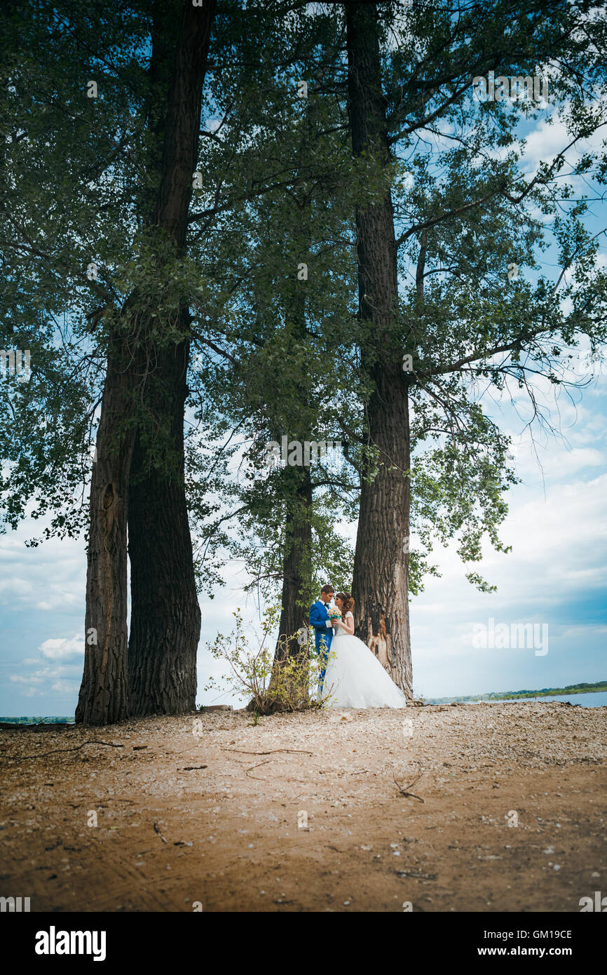 bride and groom standing and hugging on the background of trees Stock ...
