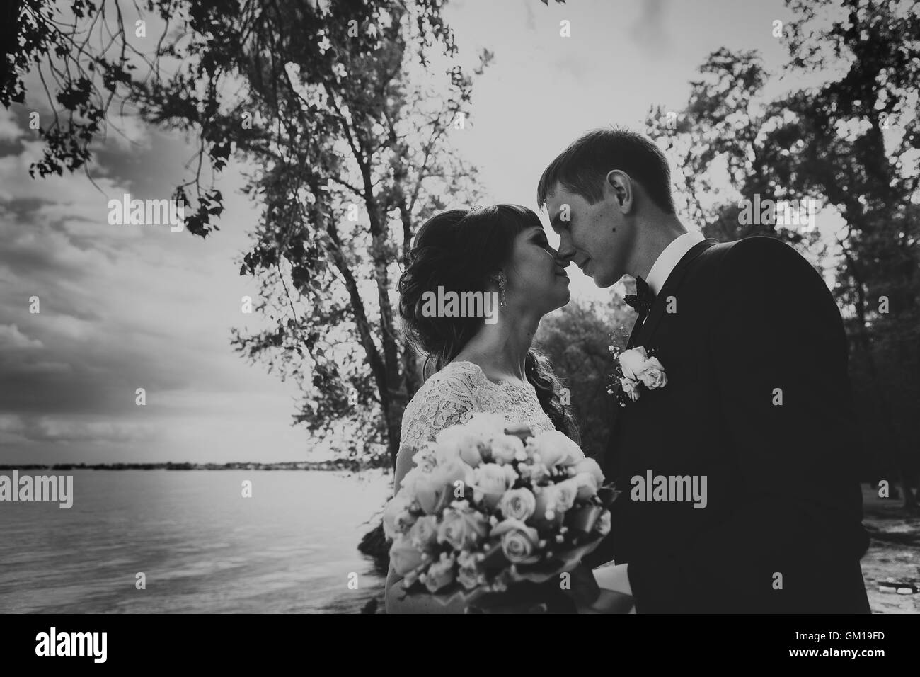 black and white photo of bride and groom standing and kissing in the ...