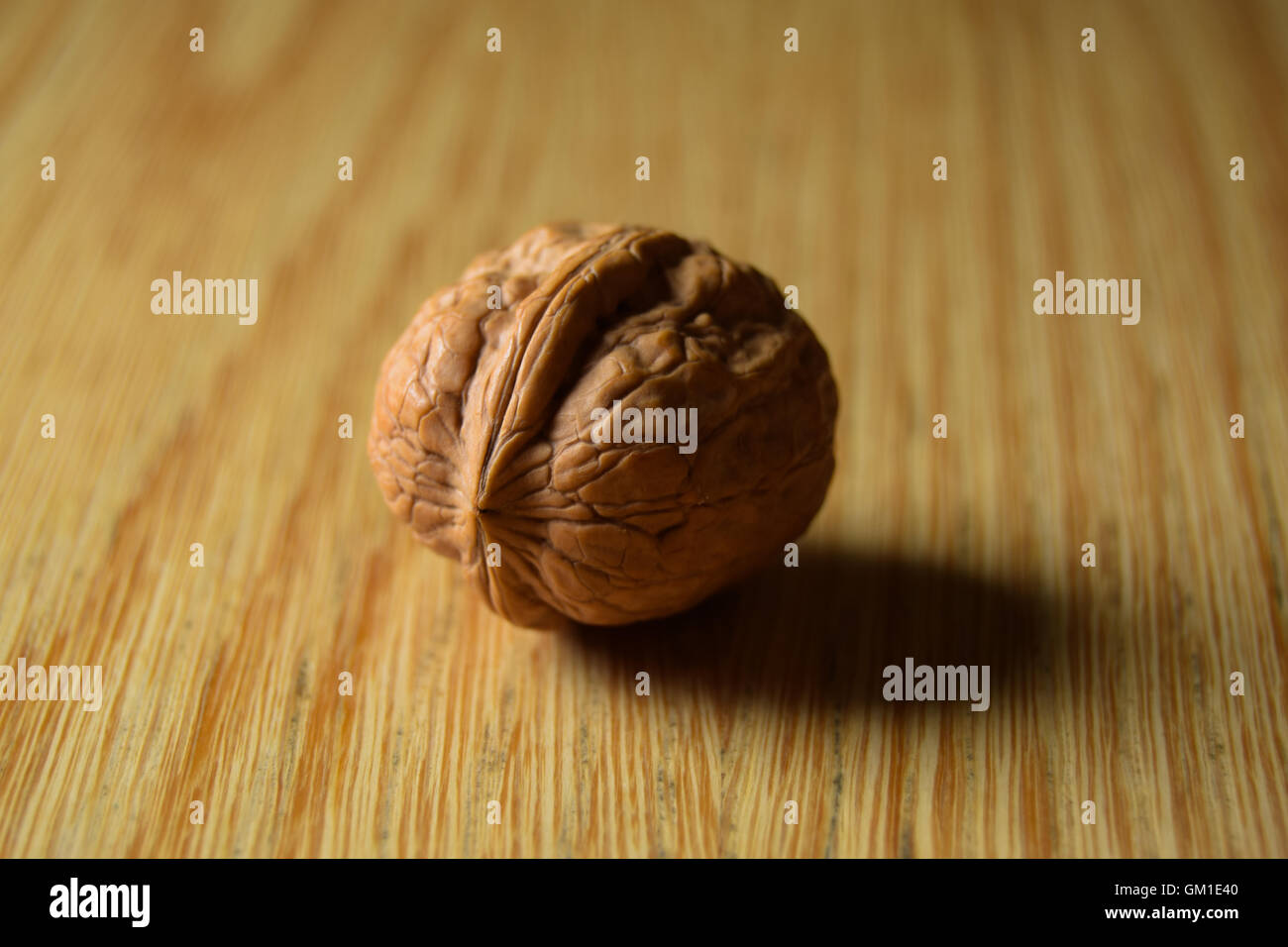 Close up of a tasty brown walnut on a wooden table, focused on subject close up Stock Photo